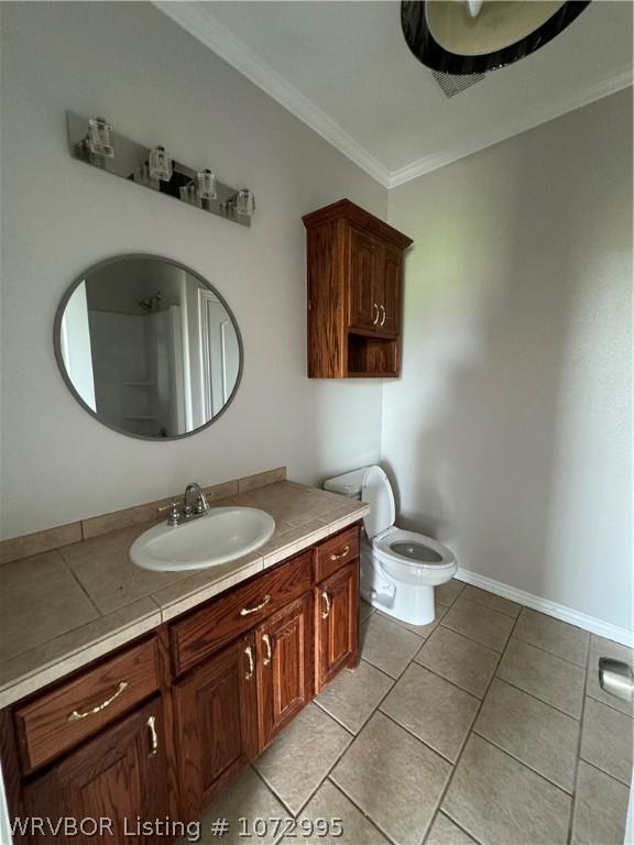 bathroom featuring toilet, vanity, tile patterned floors, and crown molding