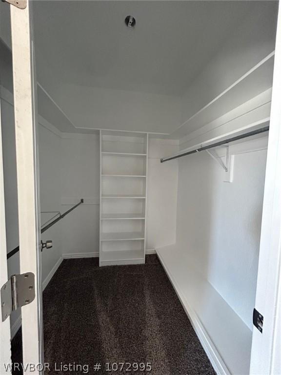 walk in closet featuring dark colored carpet