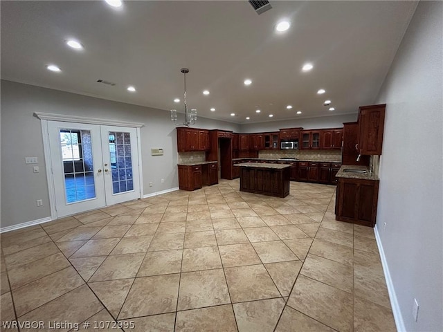 kitchen with a center island, backsplash, french doors, hanging light fixtures, and light tile patterned floors