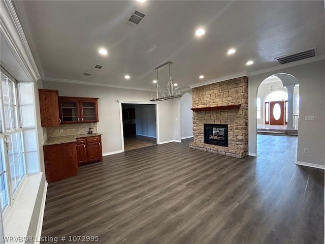 unfurnished living room with a fireplace, an inviting chandelier, dark wood-type flooring, and ornamental molding