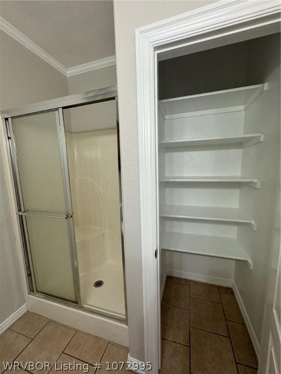 bathroom featuring tile patterned flooring, a shower with door, and crown molding