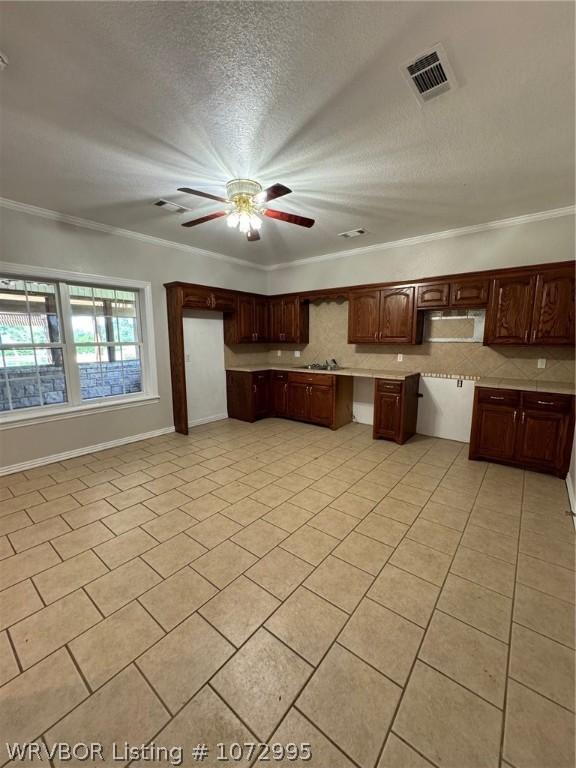 kitchen with ceiling fan, crown molding, a textured ceiling, dark brown cabinets, and light tile patterned floors