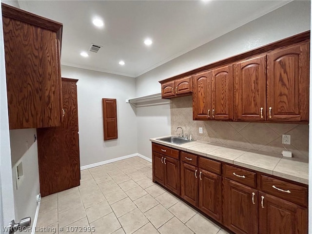 kitchen with tile counters, sink, tasteful backsplash, light tile patterned floors, and ornamental molding