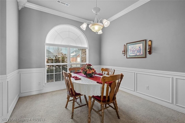 dining space with light carpet, ornamental molding, a wainscoted wall, and visible vents