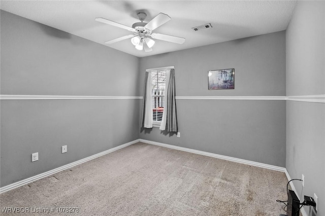 carpeted empty room with visible vents, ceiling fan, and baseboards