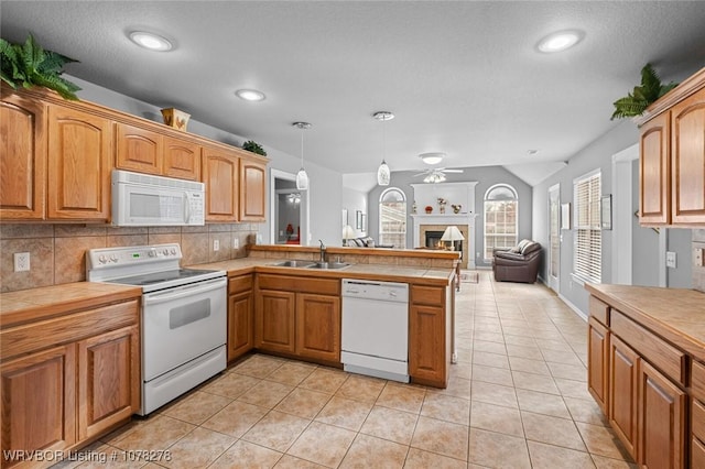 kitchen with pendant lighting, open floor plan, a sink, white appliances, and a peninsula