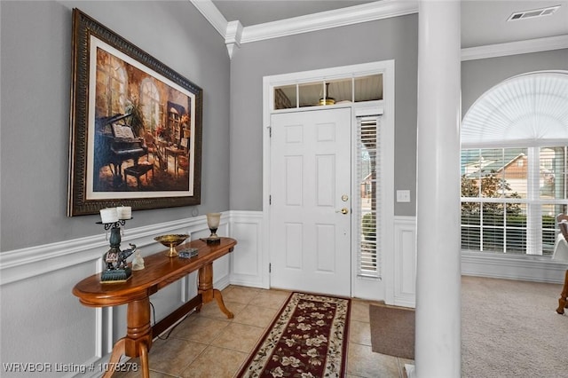 entrance foyer featuring wainscoting, light tile patterned floors, visible vents, and ornamental molding