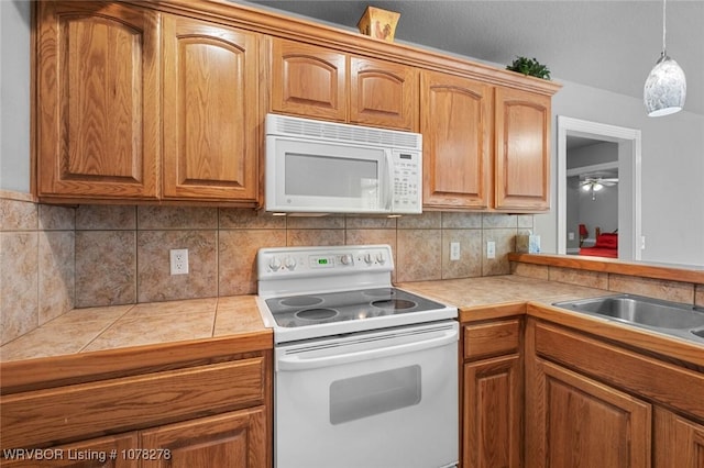 kitchen with tile countertops, white appliances, hanging light fixtures, backsplash, and brown cabinets