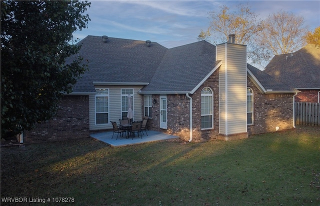 back house at dusk with a yard and a patio area