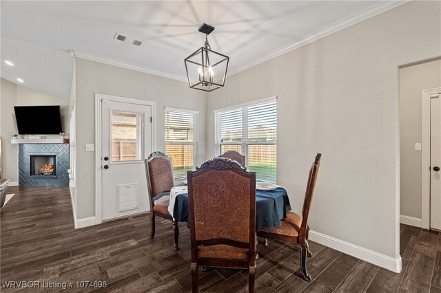 dining space with a chandelier, a fireplace, and crown molding