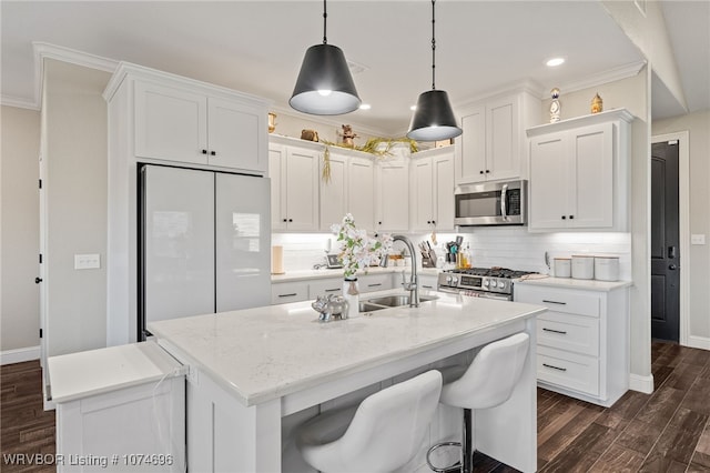 kitchen with pendant lighting, white cabinets, a center island with sink, dark hardwood / wood-style floors, and appliances with stainless steel finishes