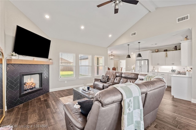 living room featuring a tile fireplace, high vaulted ceiling, ceiling fan, and beamed ceiling