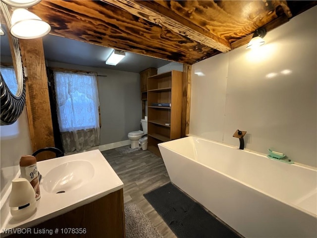 bathroom with wood-type flooring, vanity, a bathtub, and toilet