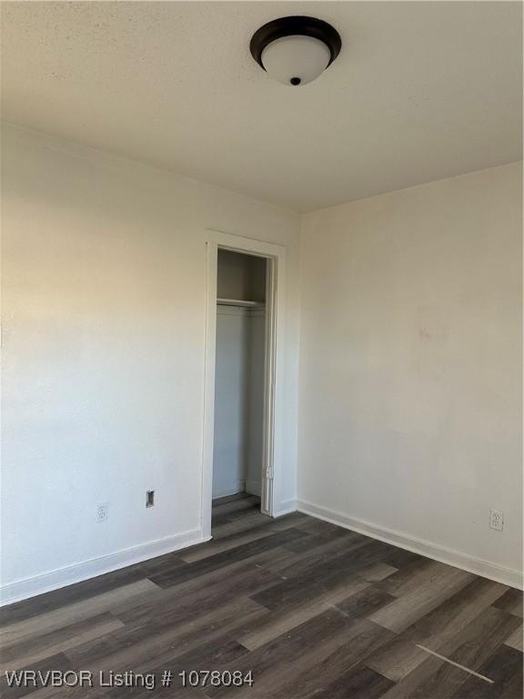 unfurnished bedroom featuring a closet and dark hardwood / wood-style floors