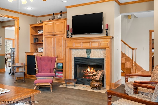 living area with baseboards, a fireplace with flush hearth, ornamental molding, wood finished floors, and stairs