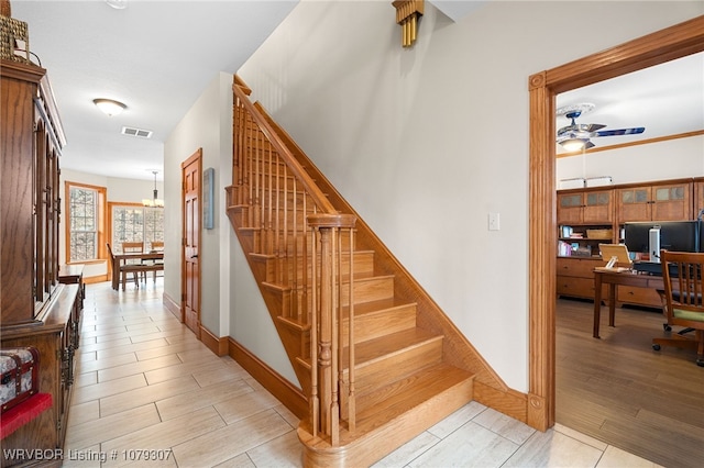 stairway with wood tiled floor, visible vents, and ceiling fan