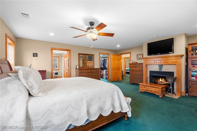 bedroom with recessed lighting, carpet flooring, visible vents, a lit fireplace, and a walk in closet