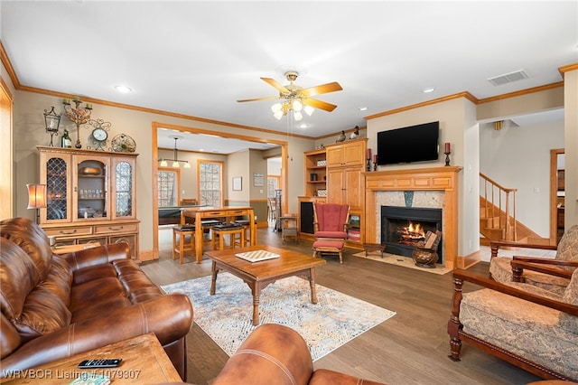 living area with a fireplace with flush hearth, a ceiling fan, visible vents, and wood finished floors