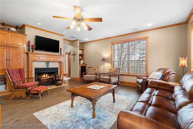 living area with baseboards, ornamental molding, wood finished floors, and a tile fireplace