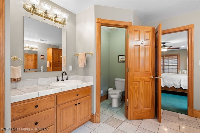 bathroom featuring toilet, ensuite bath, tile patterned floors, a textured ceiling, and vanity