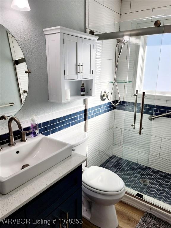 bathroom with toilet, a shower with shower door, wood-type flooring, and vanity