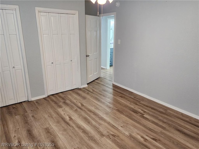 unfurnished bedroom featuring multiple closets and light hardwood / wood-style floors