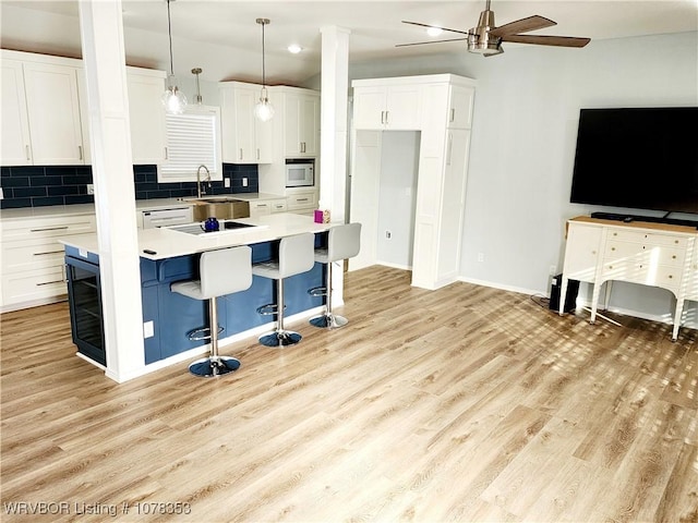 kitchen with white cabinetry, tasteful backsplash, decorative light fixtures, a kitchen island, and sink