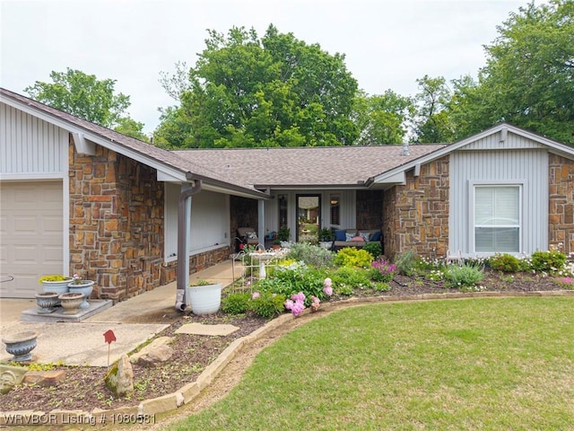 view of front of property with a garage, roof with shingles, a front yard, and stone siding