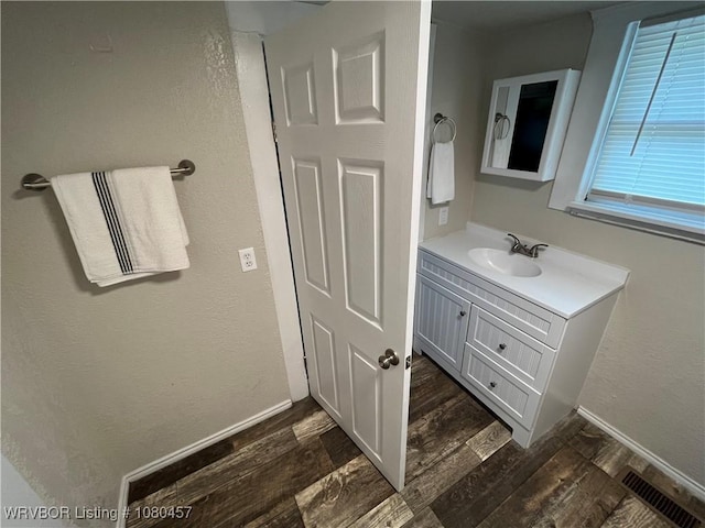 bathroom featuring baseboards, visible vents, wood finished floors, and vanity
