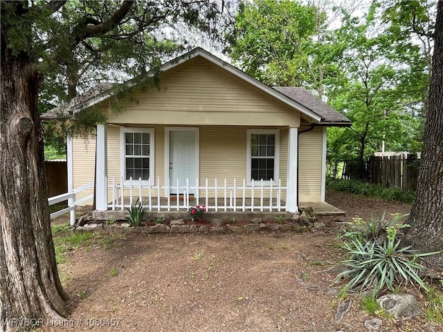 bungalow with fence, covered porch, and a shingled roof