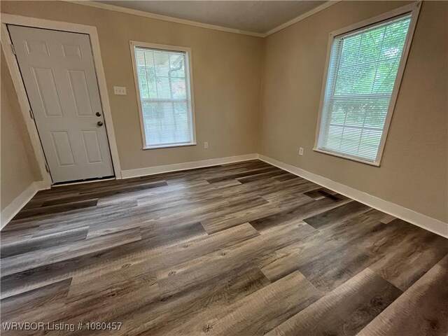 interior space featuring dark wood finished floors, baseboards, crown molding, and plenty of natural light