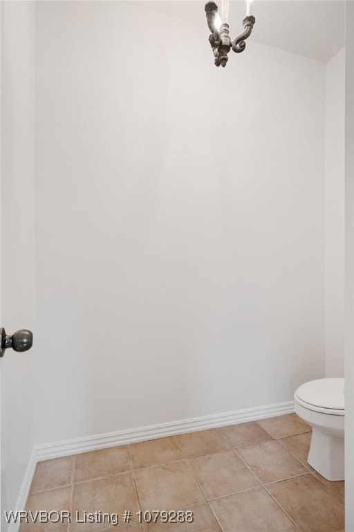 bathroom with a chandelier, tile patterned flooring, toilet, and baseboards