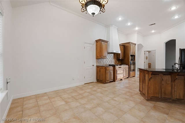 kitchen with visible vents, arched walkways, dark countertops, custom exhaust hood, and black oven