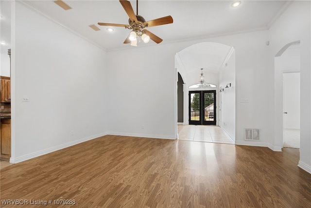 unfurnished living room with light wood-type flooring, arched walkways, visible vents, and ornamental molding