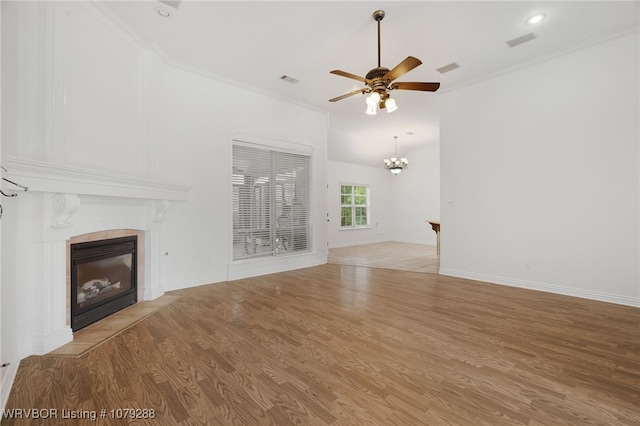 unfurnished living room featuring ceiling fan with notable chandelier, a tile fireplace, light wood-style flooring, and crown molding