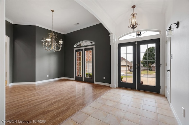 foyer entrance with light wood-type flooring, french doors, visible vents, and an inviting chandelier