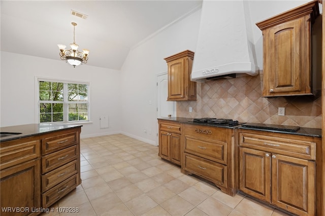 kitchen with a chandelier, premium range hood, visible vents, vaulted ceiling, and tasteful backsplash