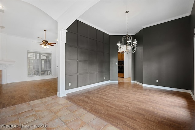 unfurnished dining area with arched walkways, crown molding, light wood-style floors, baseboards, and ceiling fan with notable chandelier