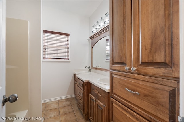 full bath with double vanity, a sink, baseboards, and tile patterned floors