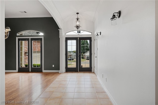 entryway featuring crown molding, visible vents, an inviting chandelier, light tile patterned flooring, and baseboards