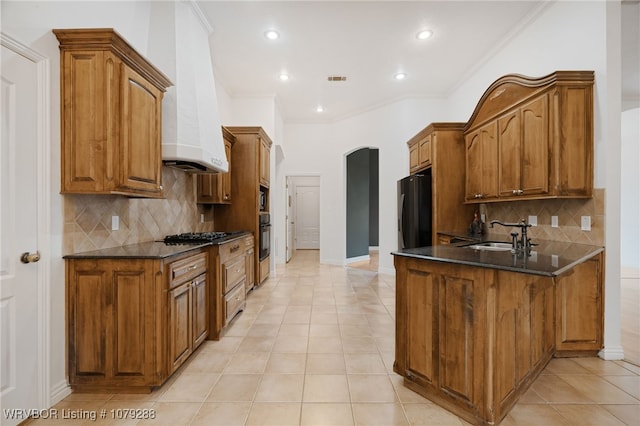 kitchen with light tile patterned floors, a sink, premium range hood, a peninsula, and black appliances