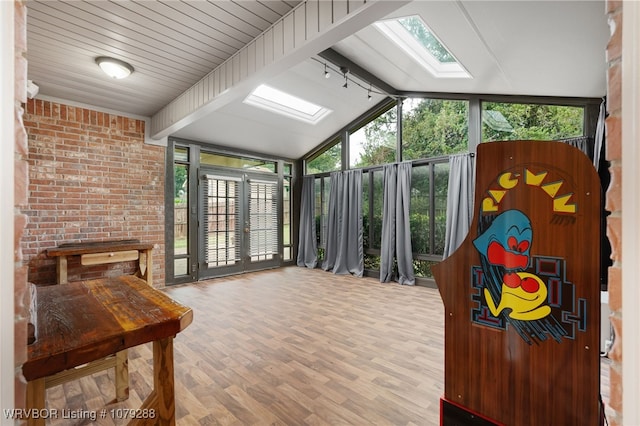 sunroom / solarium with vaulted ceiling with skylight and track lighting