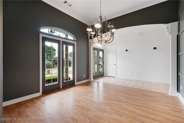 interior space with plenty of natural light, light wood-style flooring, a notable chandelier, and french doors