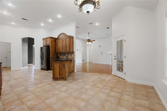 kitchen featuring arched walkways, dark countertops, visible vents, open floor plan, and black fridge