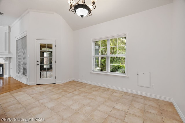 empty room featuring baseboards, a premium fireplace, a chandelier, and vaulted ceiling