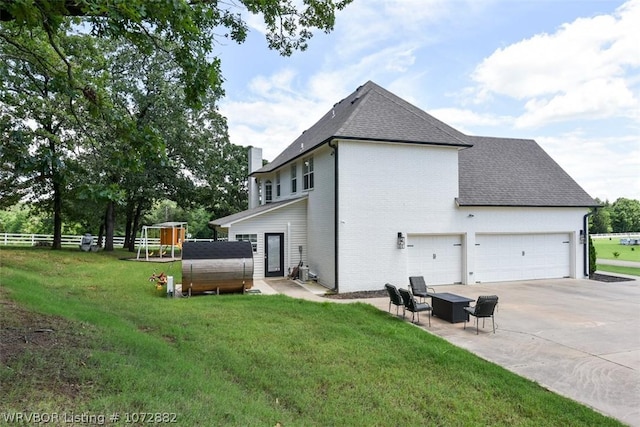 view of side of home with a yard, a garage, and a patio area