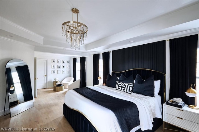 bedroom with hardwood / wood-style flooring, a raised ceiling, a notable chandelier, and crown molding