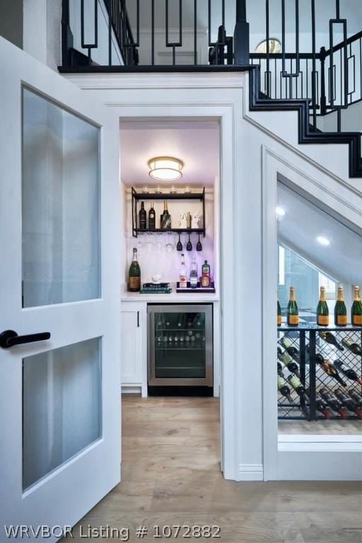 bar with white cabinetry, light wood-type flooring, and wine cooler