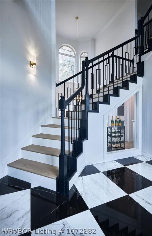 stairs with crown molding and an inviting chandelier