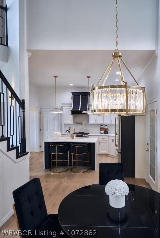 kitchen with decorative light fixtures, white cabinetry, stainless steel refrigerator, and a towering ceiling